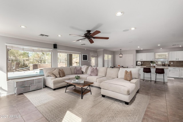 living room with crown molding, ceiling fan, and light tile patterned floors