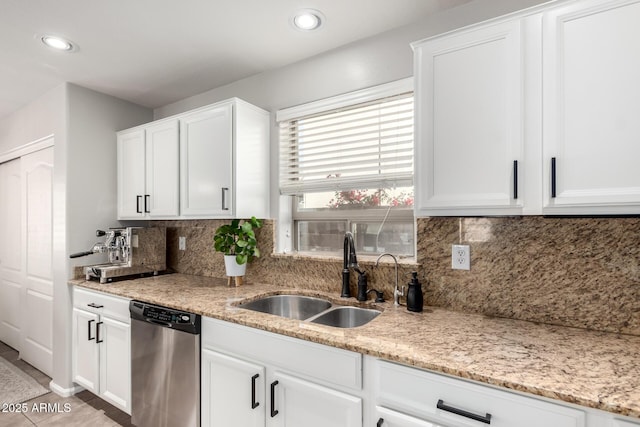 kitchen with white cabinets, stainless steel dishwasher, sink, and light tile patterned floors