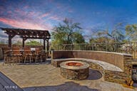 patio terrace at dusk featuring a fire pit and exterior bar