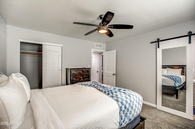 carpeted bedroom with a closet, a barn door, and ceiling fan