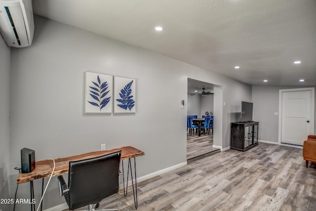 office space with ceiling fan, a wall unit AC, and light hardwood / wood-style flooring