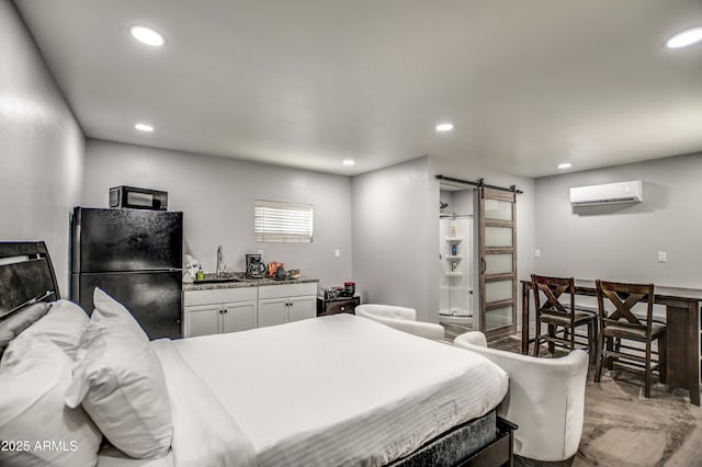 bedroom with black refrigerator, a wall mounted air conditioner, sink, and a barn door