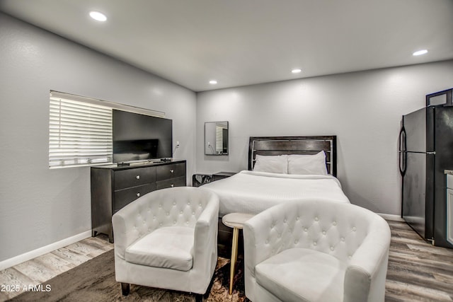 bedroom featuring black refrigerator and hardwood / wood-style floors