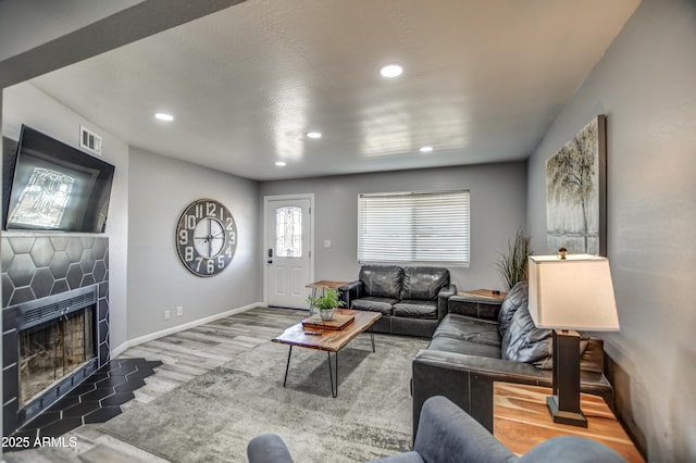 living room with a tiled fireplace and hardwood / wood-style floors