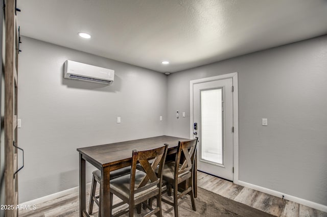 dining room with light hardwood / wood-style floors and a wall unit AC