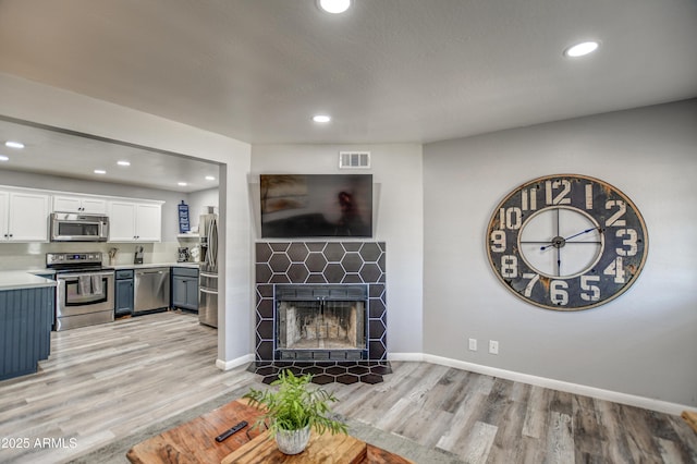 living room featuring light wood-type flooring and a fireplace