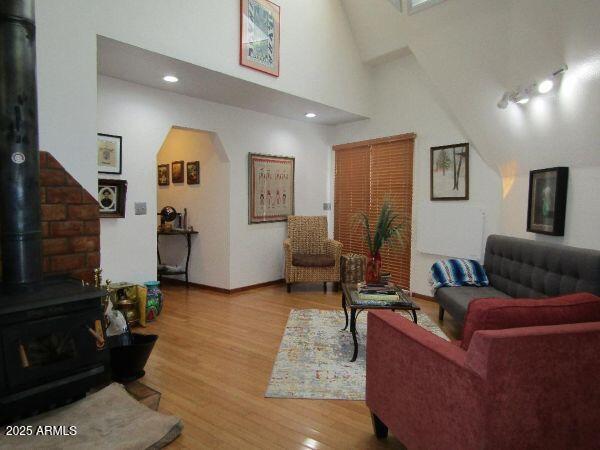 474 N Meadow Way, Payson, AZ 85541 - living room featuring a wood stove, wood finished floors, arched walkways, and a high ceiling