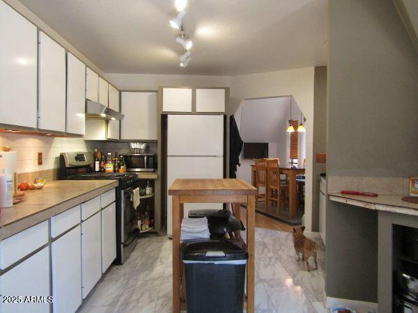 474 N Meadow Way, Payson, AZ 85541 - kitchen with stainless steel appliances, under cabinet range hood, white cabinets, light marble finish flooring, and light countertops