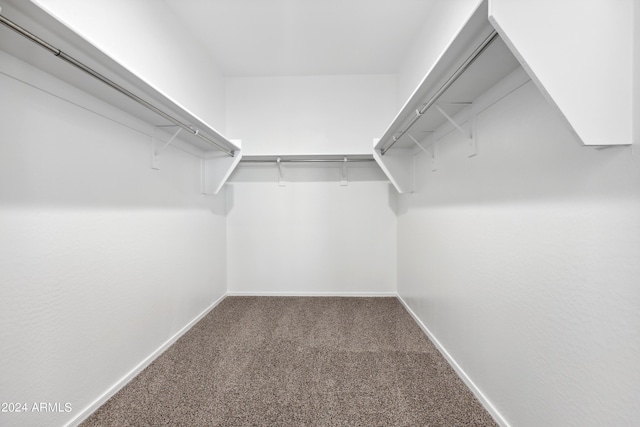 walk in closet featuring dark carpet