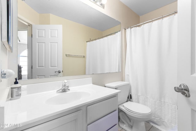 bathroom with tile patterned floors, toilet, vanity, and curtained shower