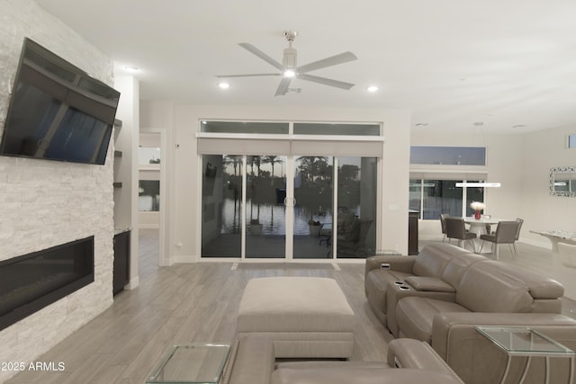 living room with light wood-type flooring, ceiling fan, a fireplace, and recessed lighting