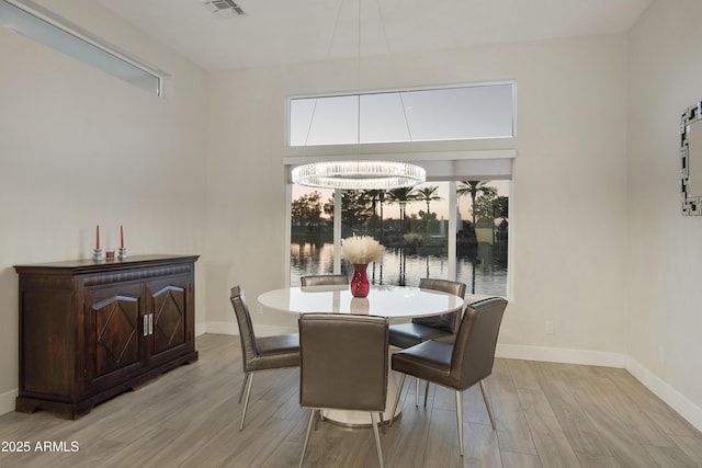 dining area with light wood-style floors, plenty of natural light, and baseboards