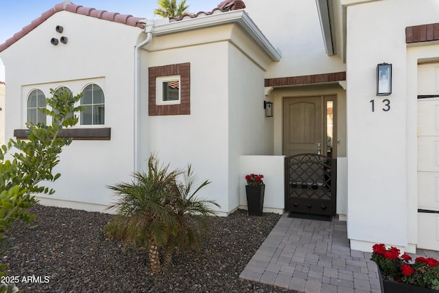 entrance to property featuring a tile roof and stucco siding