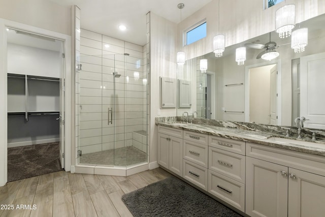 full bathroom featuring a stall shower, a walk in closet, a sink, and double vanity