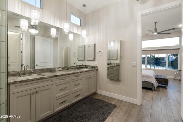 bathroom with wood finished floors, plenty of natural light, a sink, and a towering ceiling