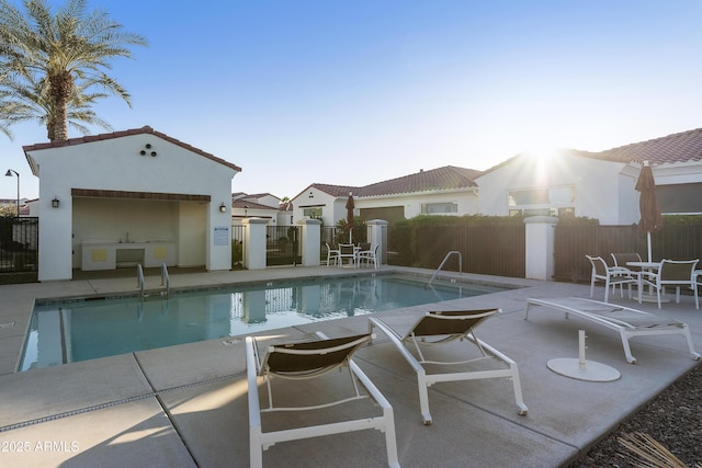 pool with a patio, an outdoor structure, and fence