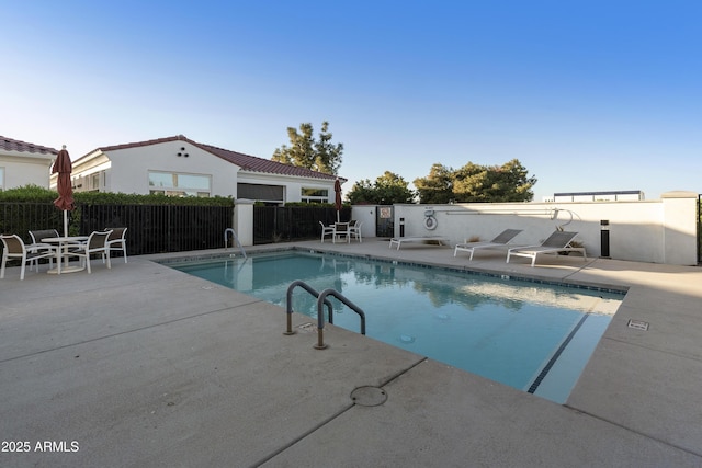 pool with a patio area and fence