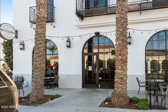 property entrance with stucco siding, french doors, and a patio