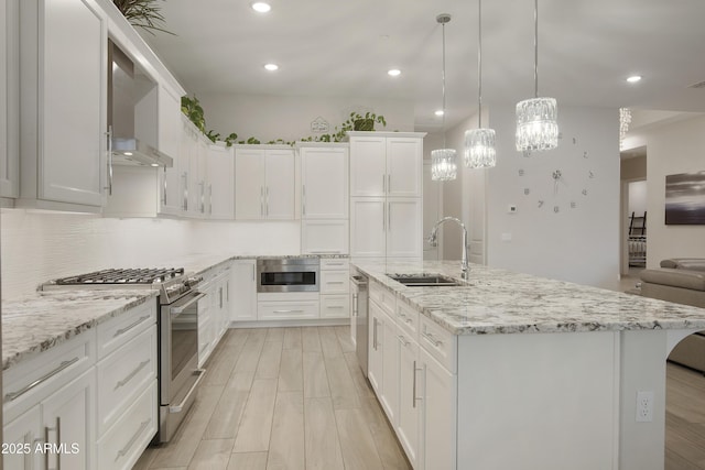 kitchen featuring stainless steel appliances, an island with sink, a sink, and white cabinetry