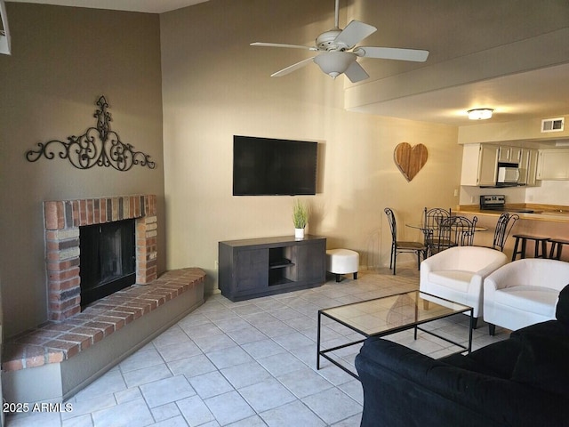 living room with ceiling fan, light tile patterned floors, and a brick fireplace