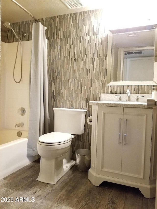 full bathroom featuring toilet, wood finished floors, shower / bathtub combination with curtain, tile walls, and vanity