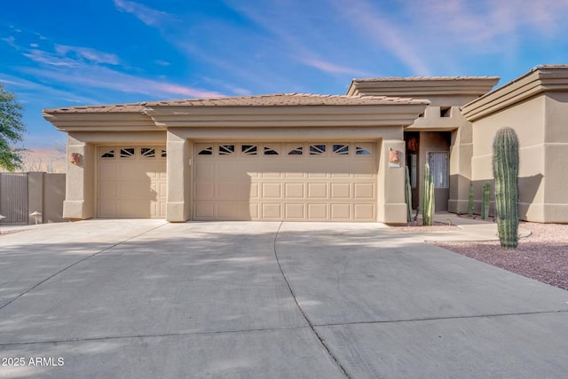 view of front facade with an attached garage, a tile roof, concrete driveway, and stucco siding