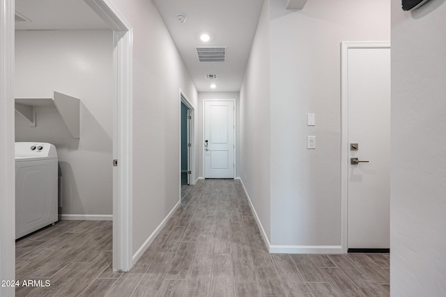 hallway with washer / dryer and light hardwood / wood-style flooring