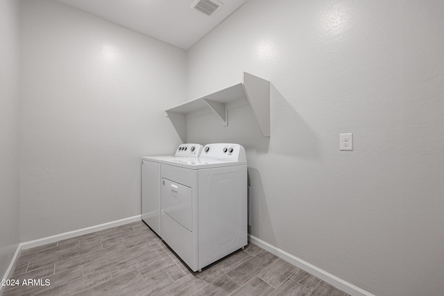 laundry room with washing machine and dryer and light wood-type flooring