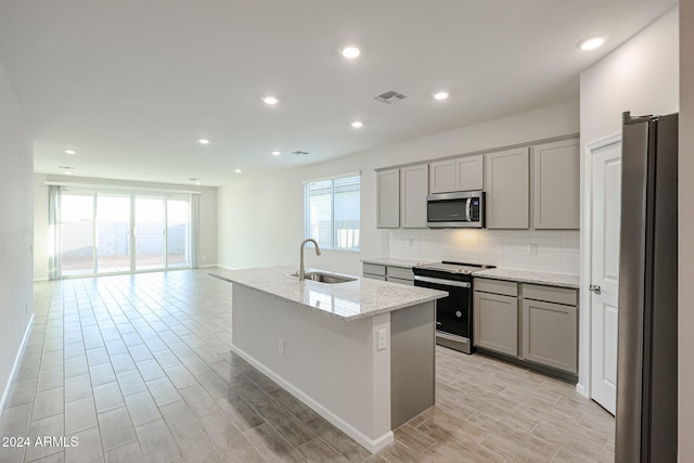 kitchen featuring a wealth of natural light, sink, appliances with stainless steel finishes, and a kitchen island with sink