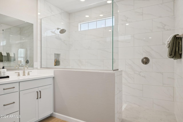 bathroom featuring hardwood / wood-style flooring, vanity, and a tile shower