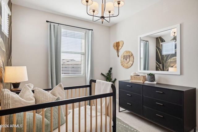 carpeted bedroom featuring an inviting chandelier and a nursery area