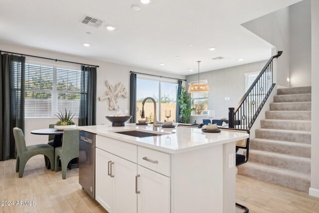 kitchen featuring white cabinetry, sink, an island with sink, and light hardwood / wood-style floors