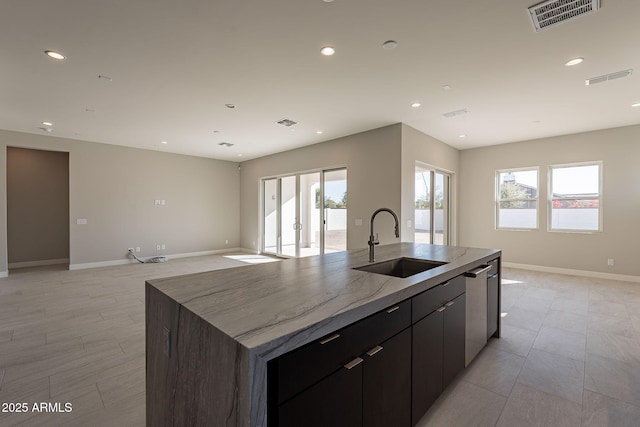 kitchen with sink, an island with sink, stainless steel dishwasher, and dark brown cabinets