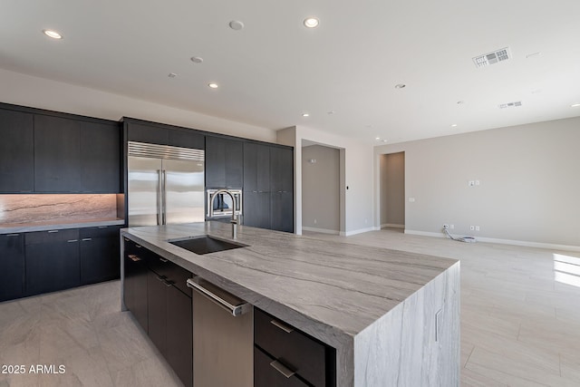 kitchen with appliances with stainless steel finishes, sink, a large island with sink, and tasteful backsplash