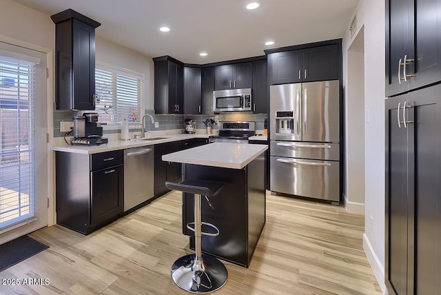 kitchen with a center island, a kitchen breakfast bar, sink, light wood-type flooring, and appliances with stainless steel finishes