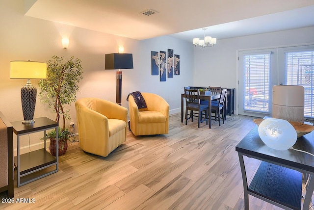 living room with an inviting chandelier and light hardwood / wood-style flooring