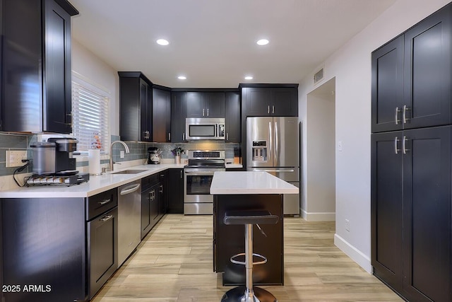 kitchen featuring sink, a center island, stainless steel appliances, backsplash, and a kitchen bar