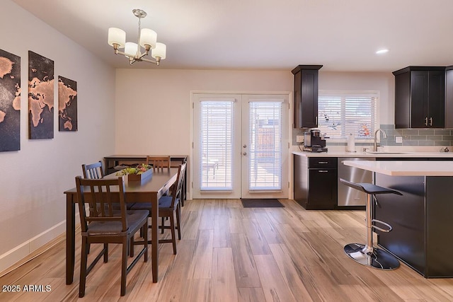 dining space featuring a chandelier, sink, and light hardwood / wood-style flooring