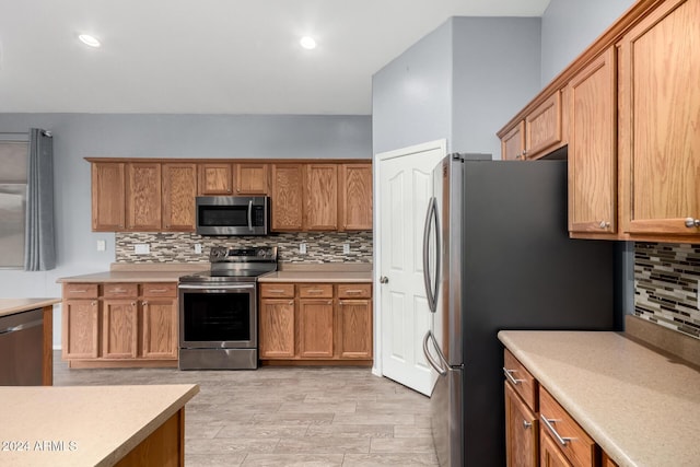 kitchen with appliances with stainless steel finishes, light hardwood / wood-style floors, and tasteful backsplash