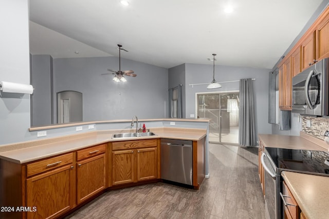 kitchen with hardwood / wood-style floors, appliances with stainless steel finishes, lofted ceiling, hanging light fixtures, and sink