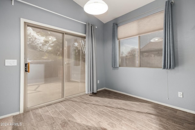 spare room with vaulted ceiling and hardwood / wood-style flooring