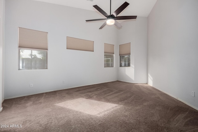 carpeted spare room with ceiling fan and high vaulted ceiling