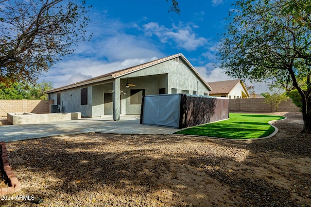 back of property with ceiling fan, a yard, and a patio