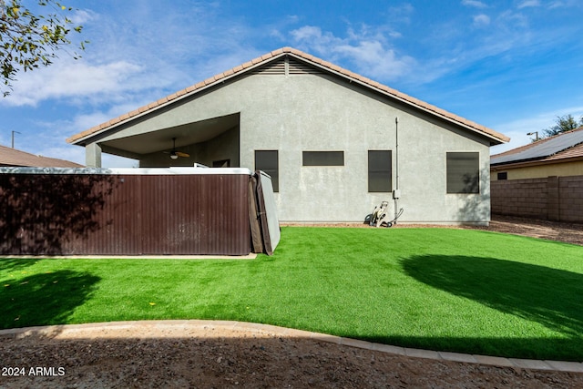 back of house with ceiling fan and a yard