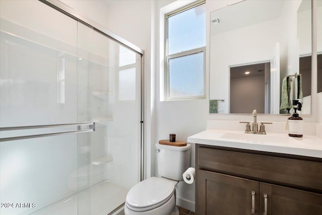 bathroom with a shower with door, vanity, and toilet