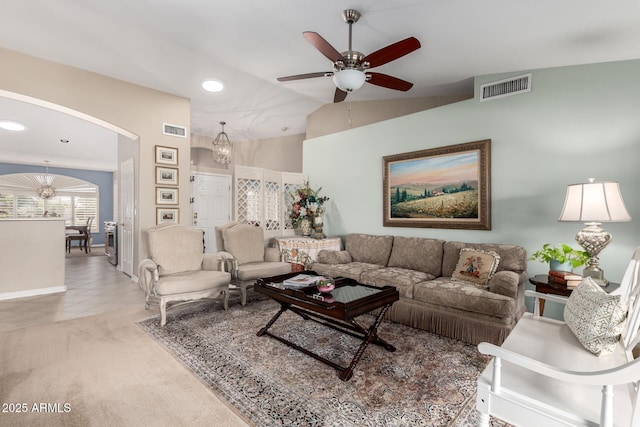 carpeted living room featuring vaulted ceiling, visible vents, arched walkways, and ceiling fan with notable chandelier