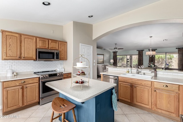 kitchen featuring a sink, light countertops, appliances with stainless steel finishes, a center island, and pendant lighting