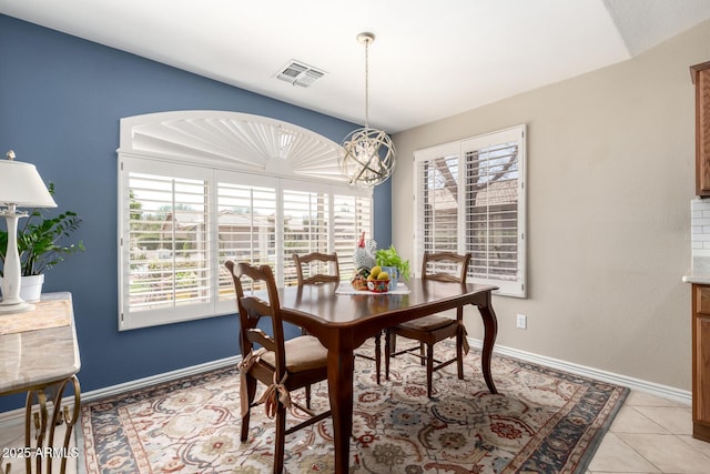 dining space with light tile patterned floors, a notable chandelier, visible vents, and baseboards