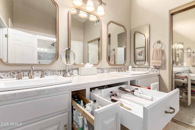 bathroom featuring a tile shower, double vanity, tile patterned flooring, and a sink