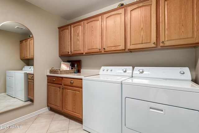 laundry room with light tile patterned flooring, independent washer and dryer, cabinet space, and baseboards